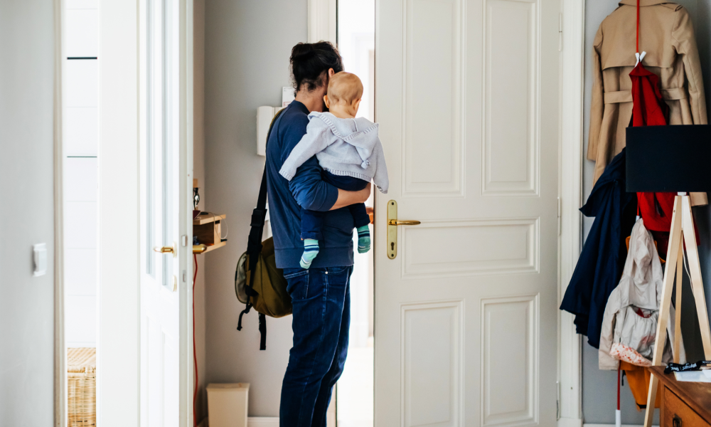 man holding a baby leaving through the front door