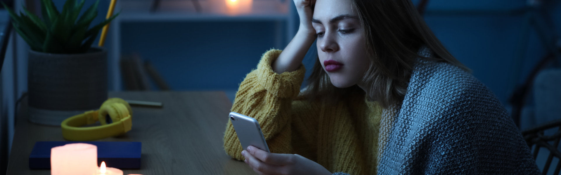 teenage girl looking at their phone in the light of battery powered candles during a power outage
