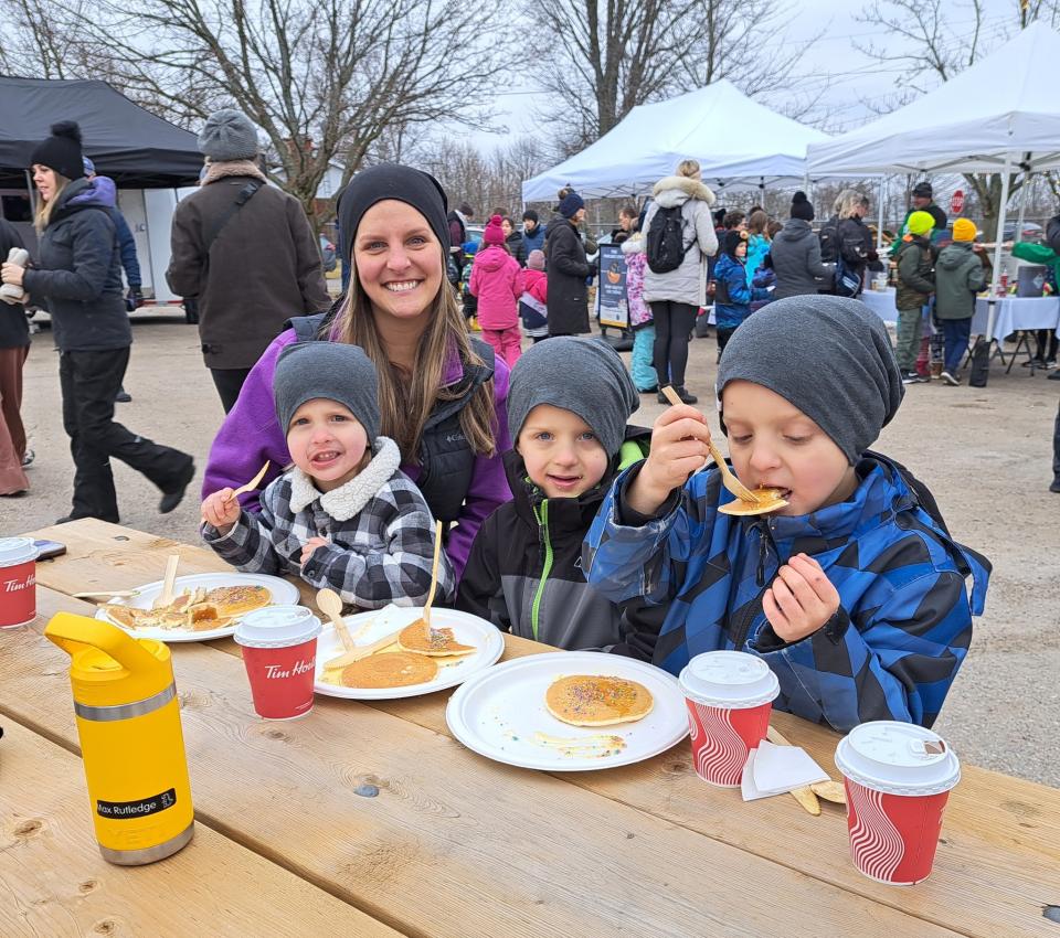 young family enjoying pancakes and hot chocolate at a picnic table 