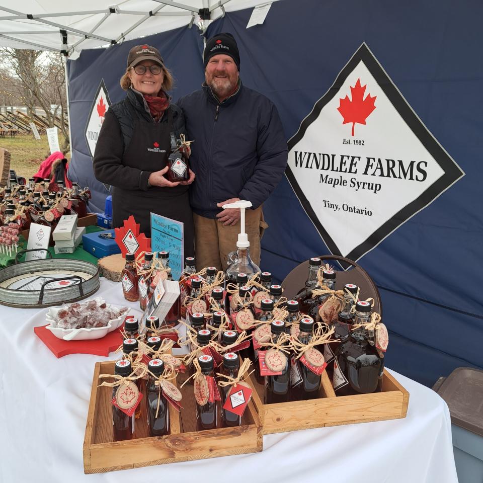 Peter and Ann from Windlee Farms at their maple syrup booth - many maple products are displayed on the table in front of where they are standing