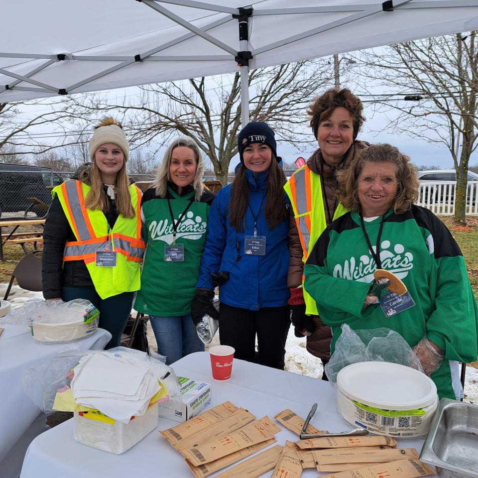 Group photo of volunteers and a Tiny staff member at the pancake serving booth all smiling for the camera