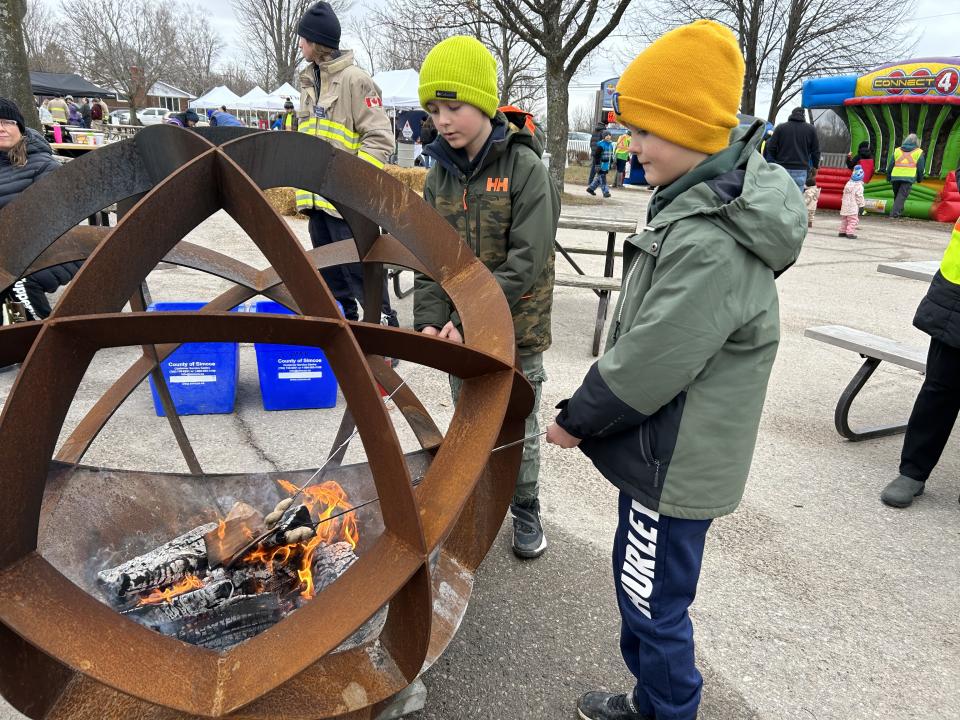 Two young boys roasting marshmallows in the fire pits