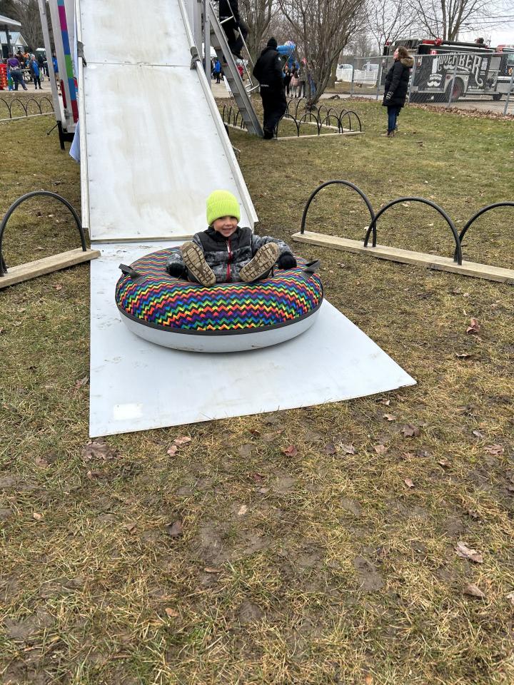 young child coming down the Snow Valley tubing hill in a large and colourful tube