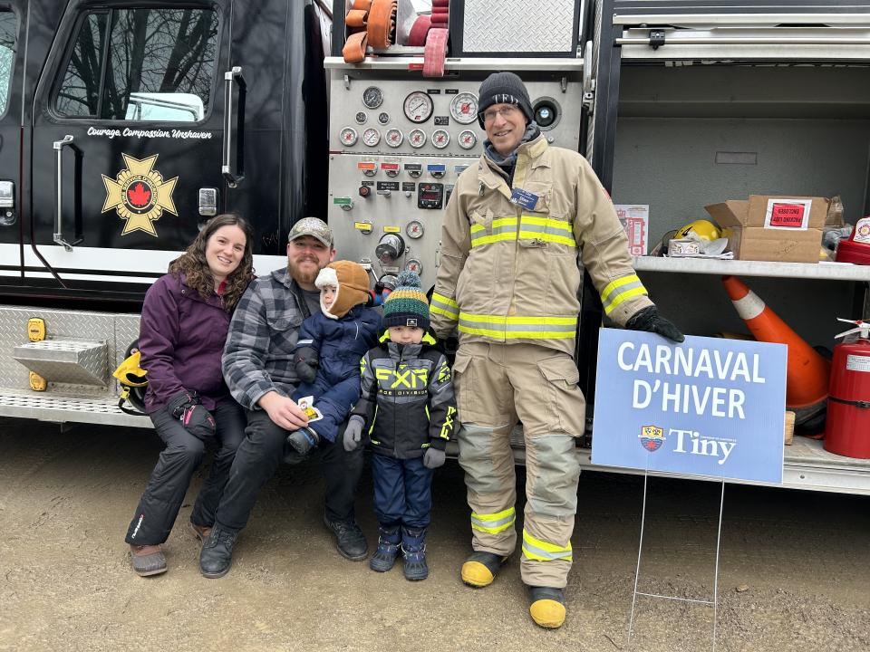 Young family posing for a photo with a Tiny volunteer firefighter in front of the Movember fire truck