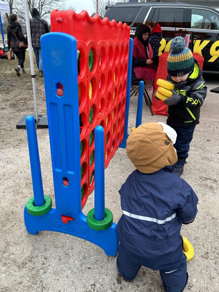 young children playing Connect 4 in front of the Rock 95 booth