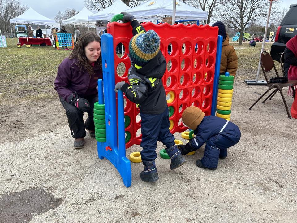 young children and a parent playing Connect 4 in front of the Rock 95 booth