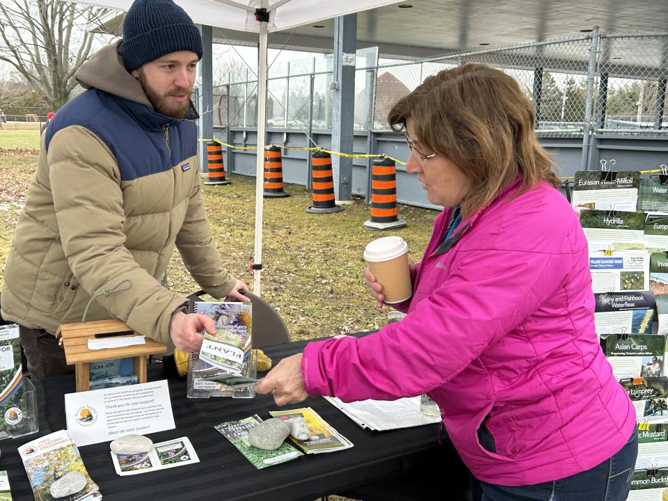 woman talking to the staff/volunteer at the Severn Sound Environmental Association booth while drinking hot apple cider