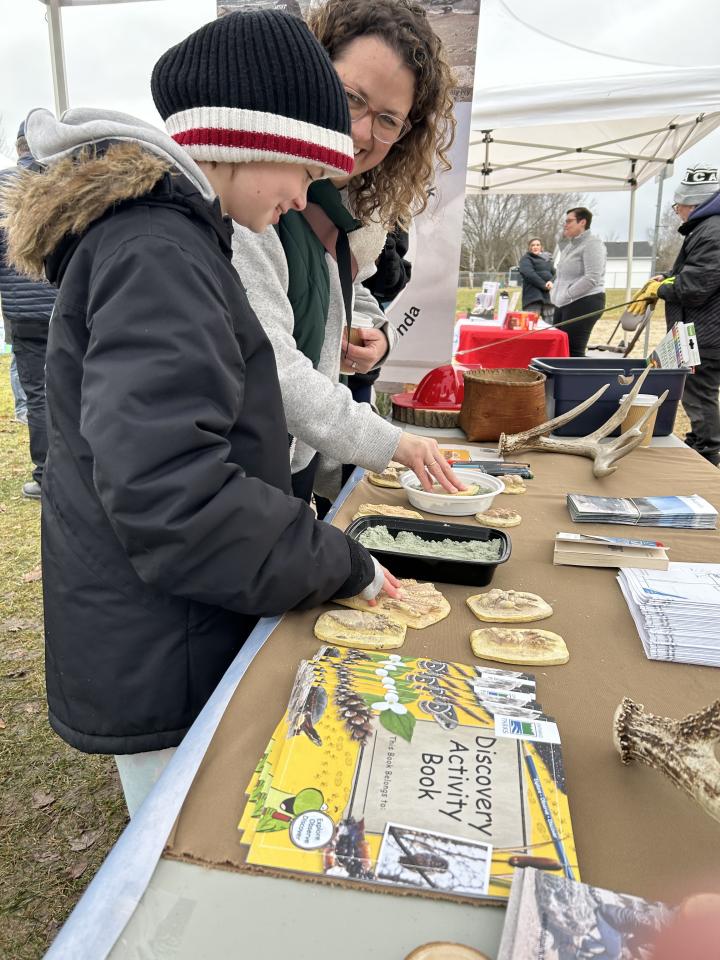 Family having fun and interacting with the activities at the Friends of Awenda booth