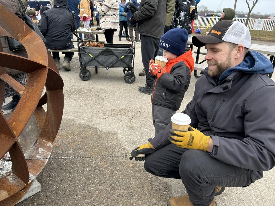 Father roasting marshmallows with their son - both enjoying hot apple cider