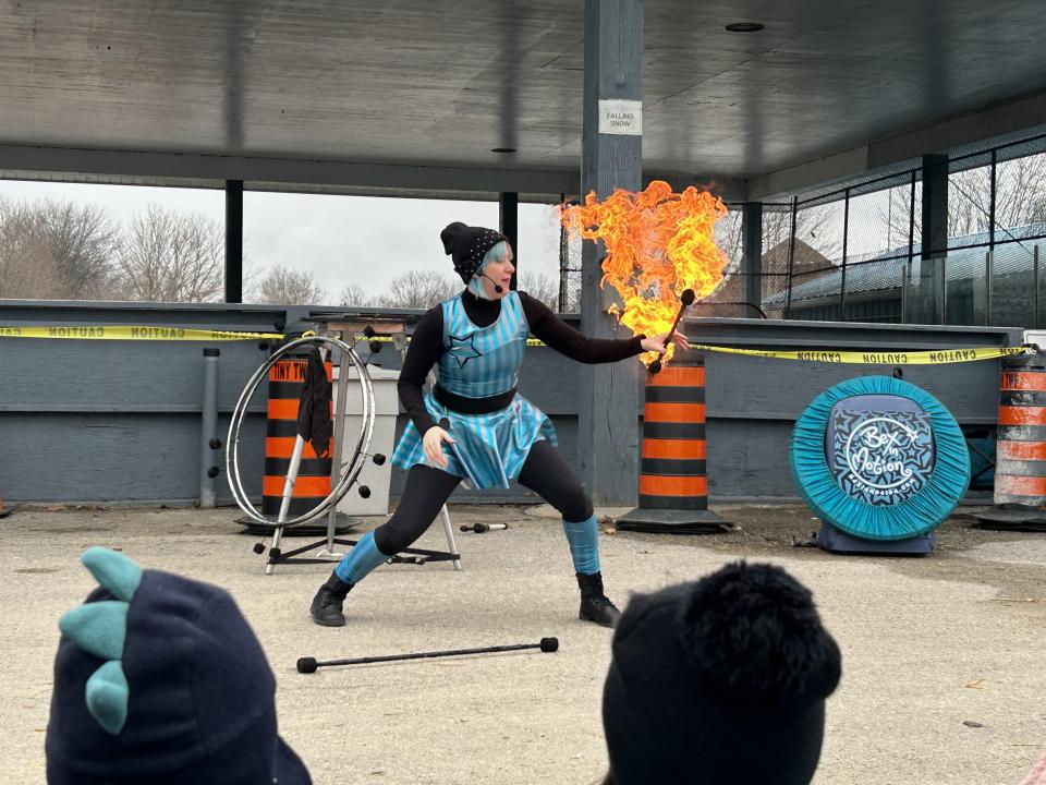 Bex in Motion during their fire performance holding a fire stick with a large burst of fire