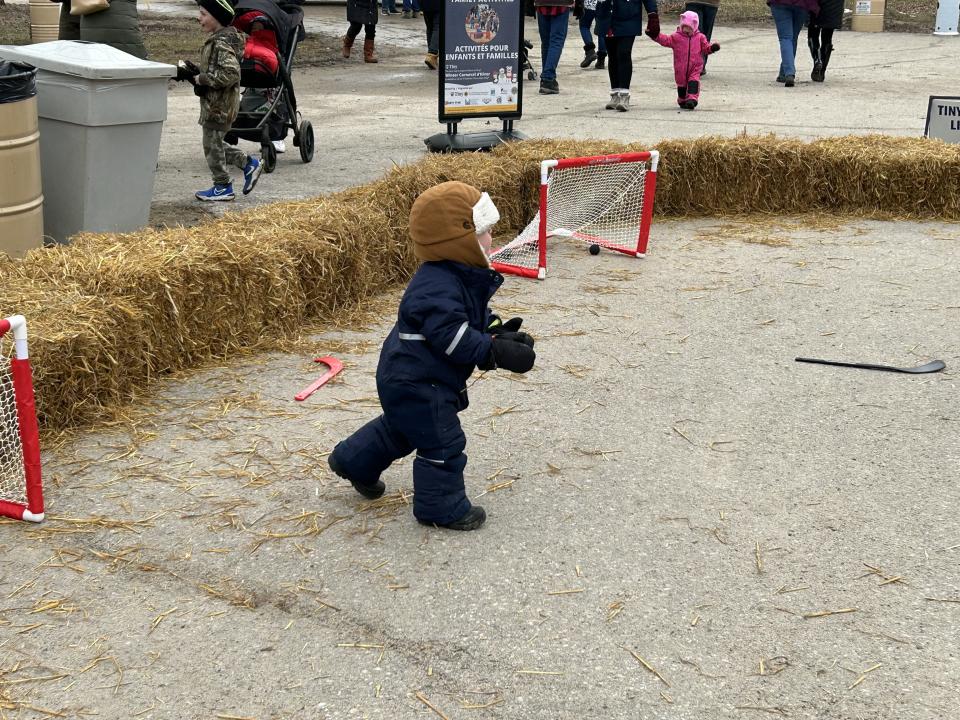 young child playing with a ball in the Lions Club's mini stick arena that is surrounded by straw bales