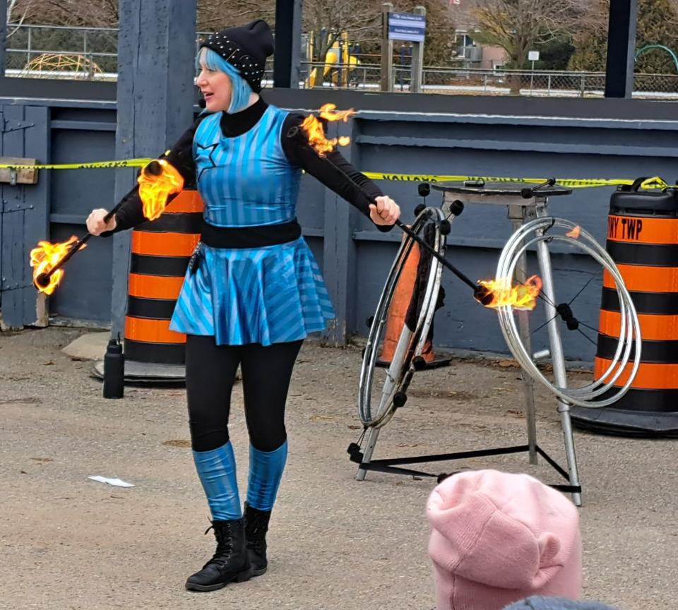 Bex in Motion during their fire performance holding a flaming stick in each hand