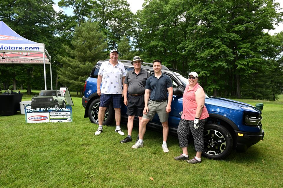 Golf foursome posing in front of the Bourgeois Motors hole in one challenge