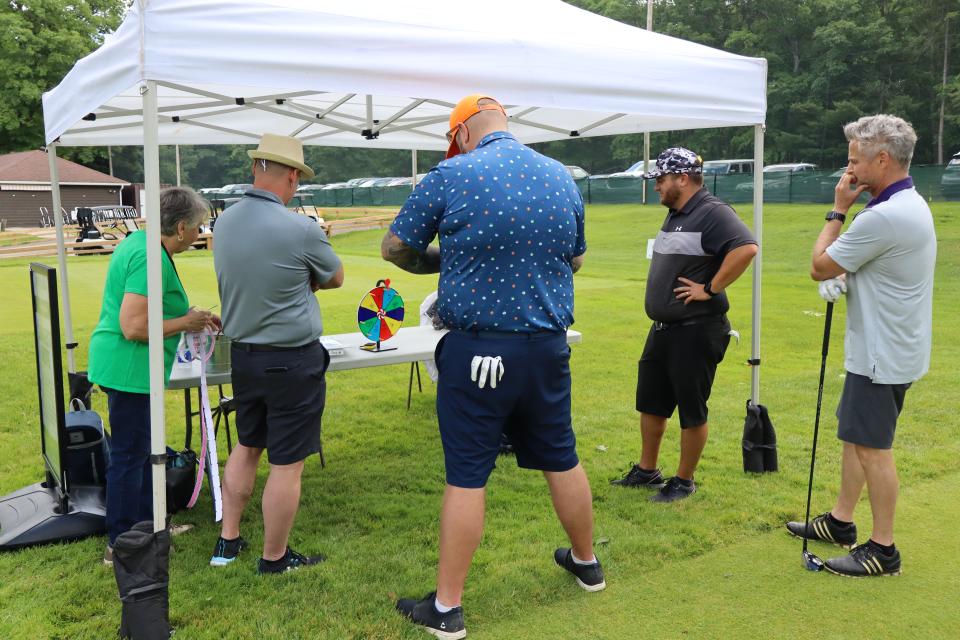 Golfers playing a game at Deputy Mayor Miskimins station to win raffle tickets