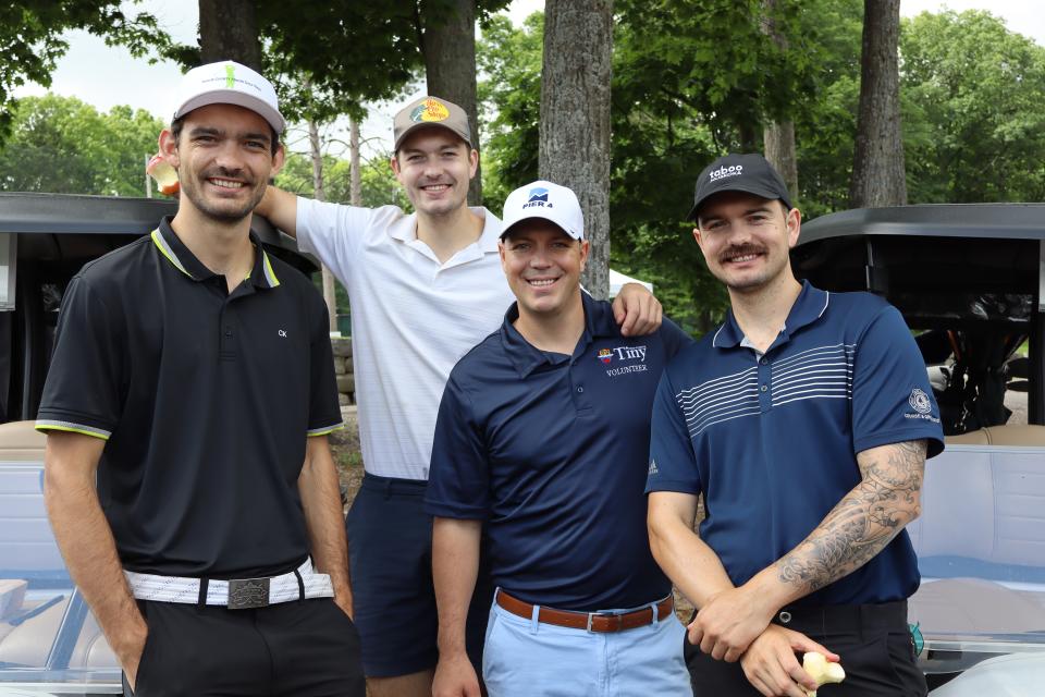 Men's golf foursome in front of their carts