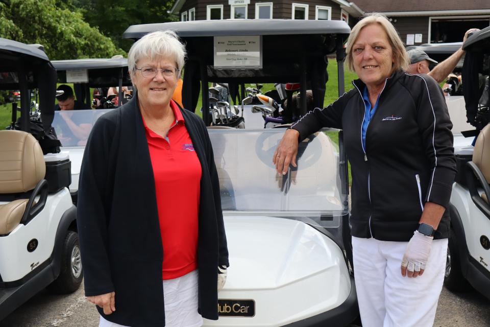 Women's pair posing in front of their golf cart