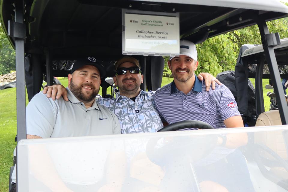 Three men sitting inside their golf cart before the start of the tournament