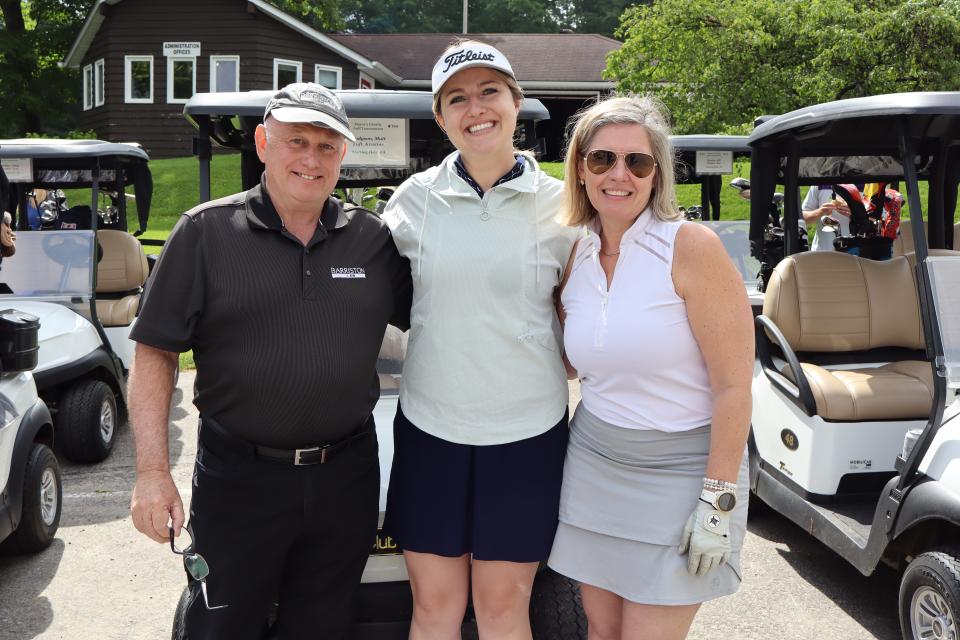 A man and two women posing in front of their golf carts before starting the tournament