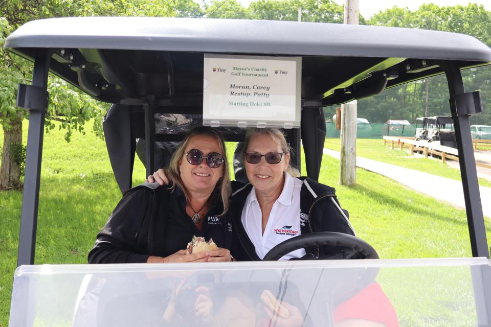 two women sitting inside of their golf cart having lunch