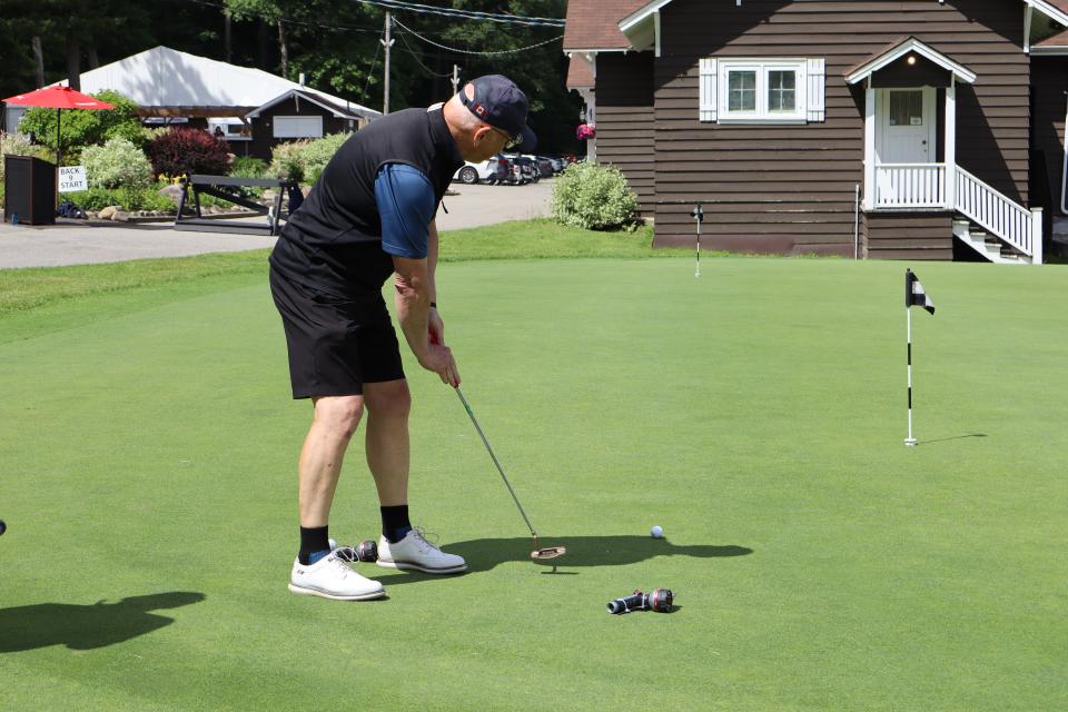 Male golfer at the Mayor's putting challenge with the clubhouse in the background