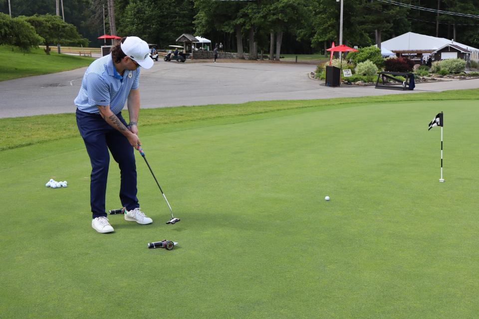 Male golfer at the Mayor's putting challenge with the clubhouse in the background