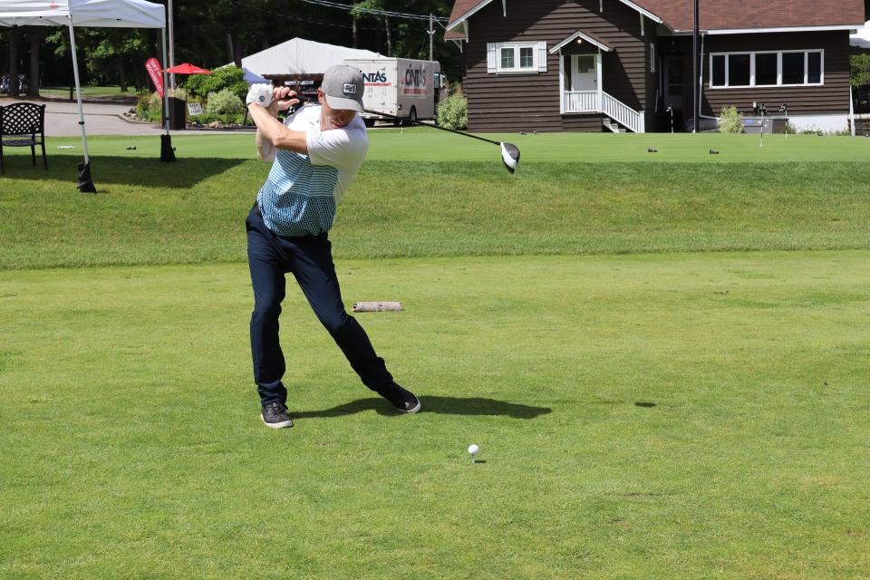 Male golfer about to swing at the closest to the line challenge with the clubhouse in the background