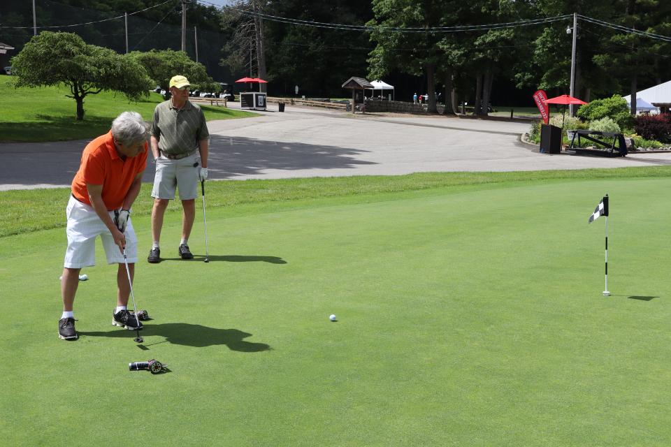 Male golfer at the Mayor's putting challenge with their partner in the background