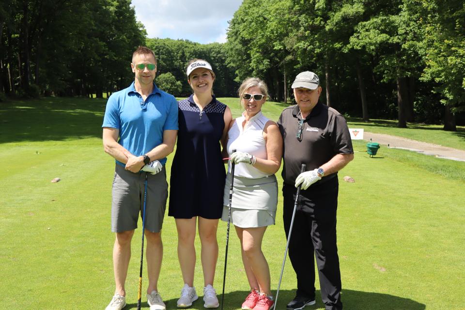 Mixed golf foursome on the greens at the longest drive contest hole 