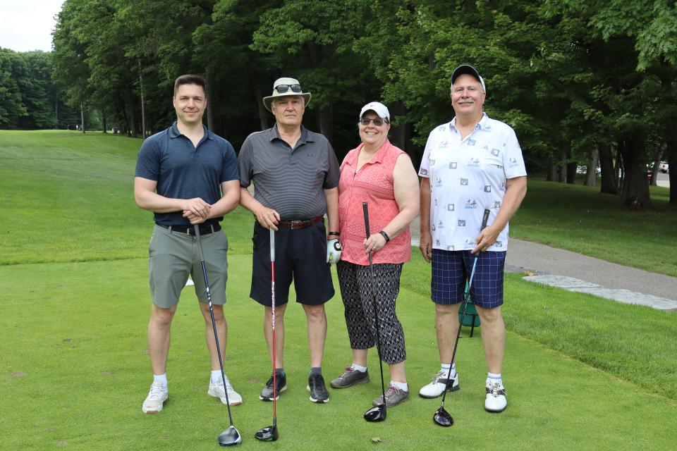 Mixed golf foursome on the greens at the longest drive contest hole all posing with their clubs 