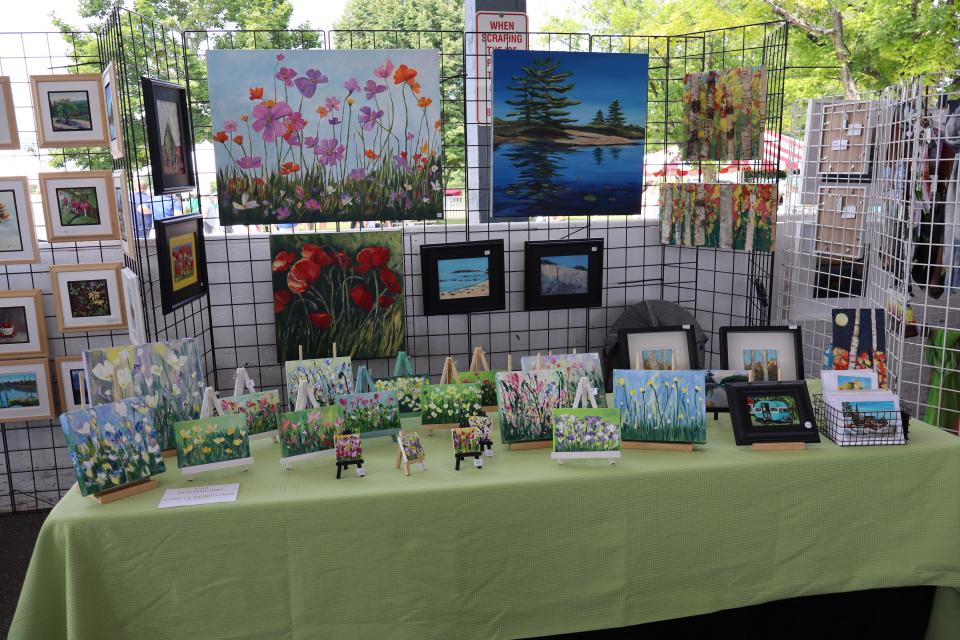 Image of various paintings set up on and behind a green table