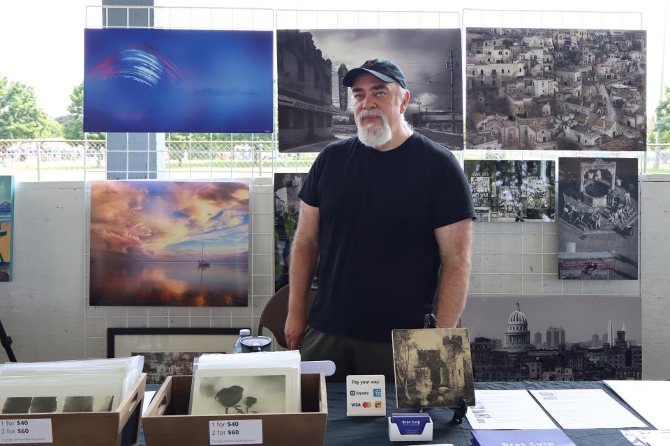 Man standing in their art booth at the vendor fair