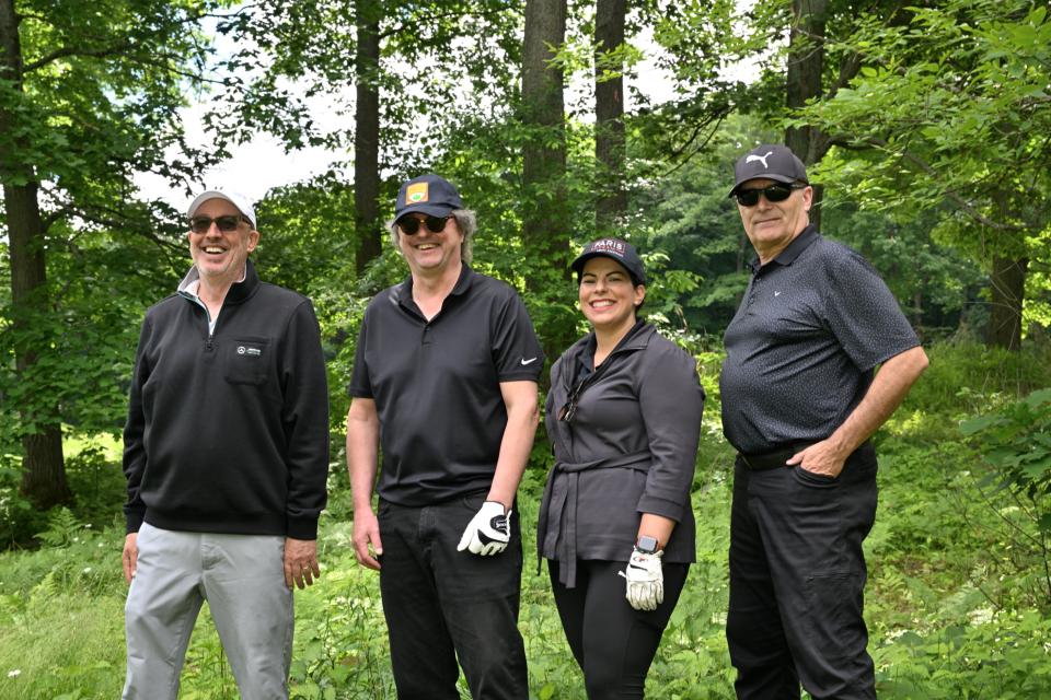 Mixed golf foursome out on the greens with a treed area in the background