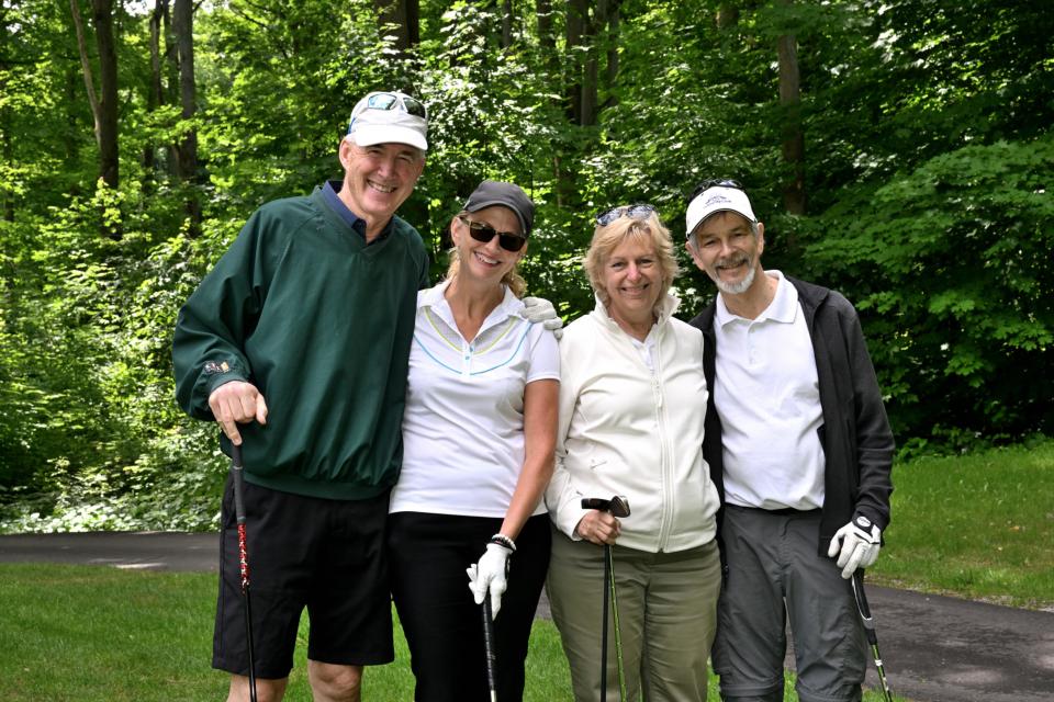 Mixed golf foursome out on the greens with a pathway and trees in the background