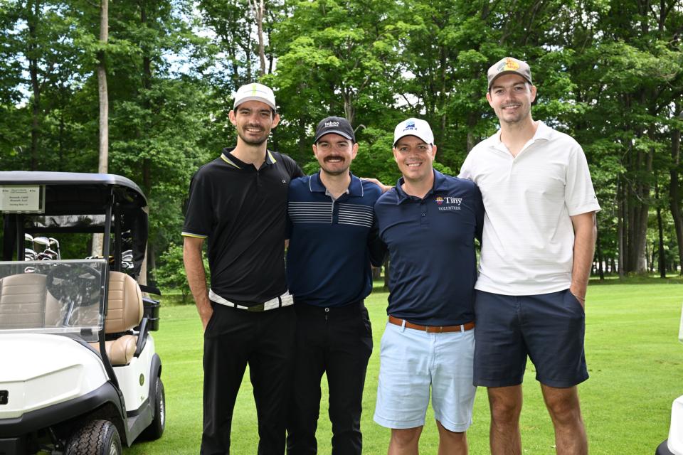 Men's golf foursome out on the greens, standing between their golf carts