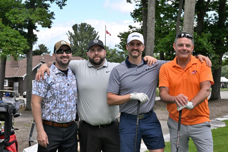 Men's golf foursome with a pathway and the clubhouse in the background