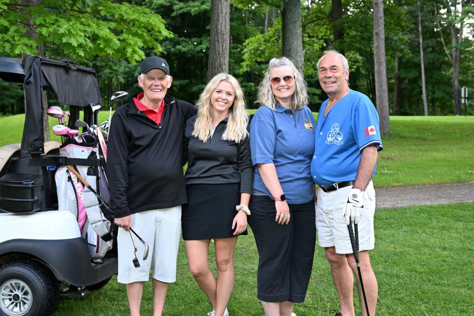 Mixed golf foursome out on the greens standing next to one of their carts