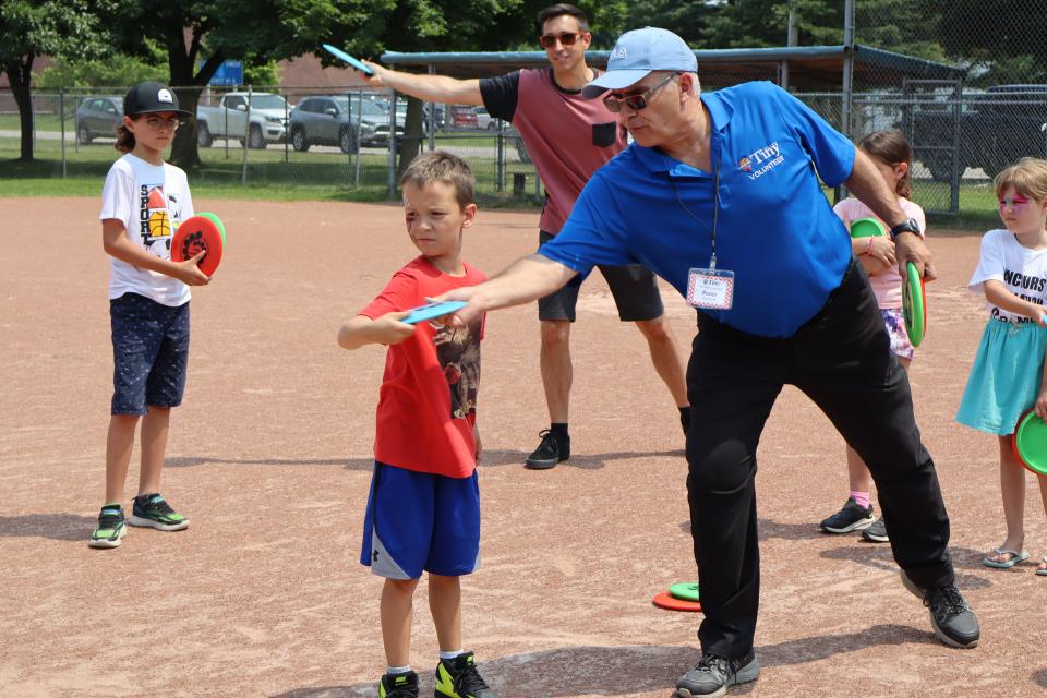 Tiny volunteer showing a young boy how to throw a frisbee