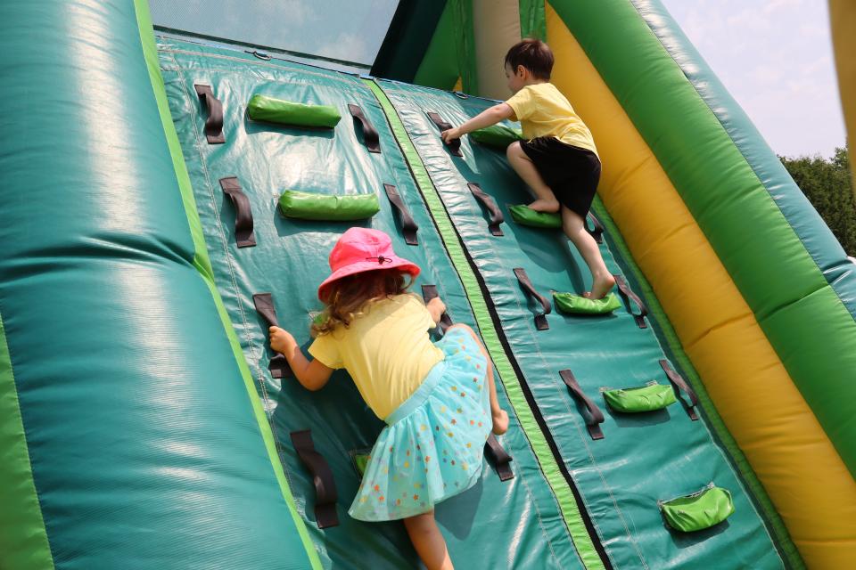 Two young children climbing a large green inflatable