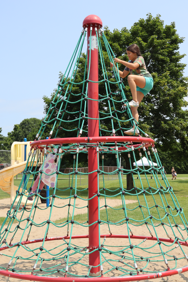 Two young girls climbing on the playground equipment