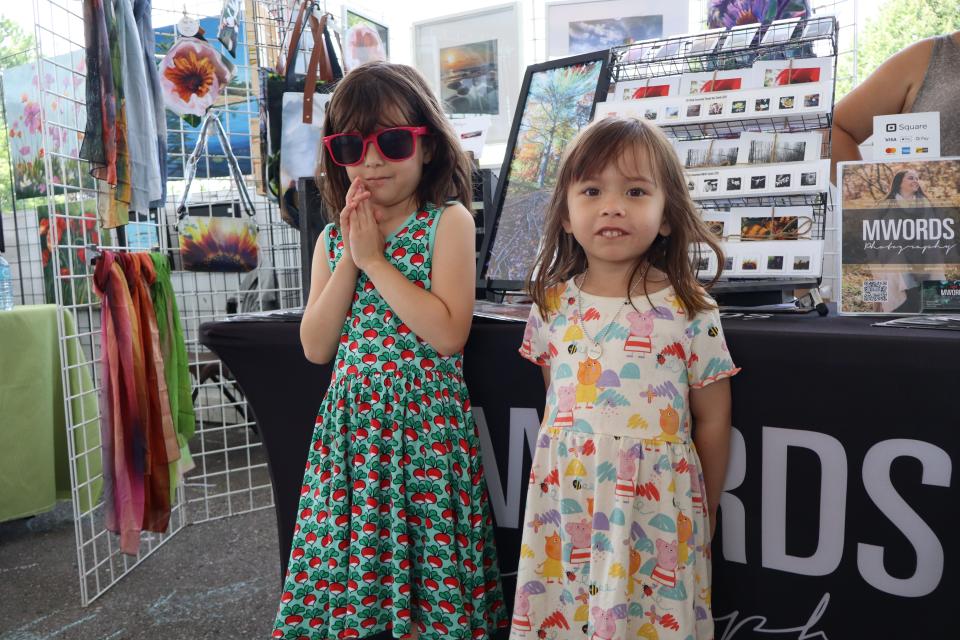 Two young girls in colourful dresses exploring the vendor fair