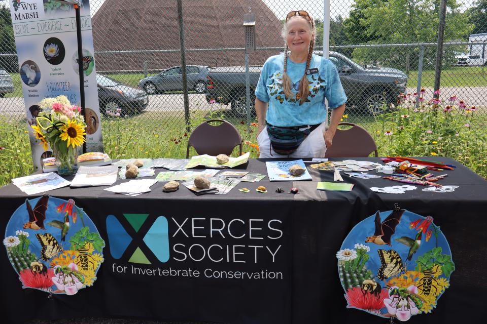 Woman posing behind the Xerces Society for Invertebrate Conservation table