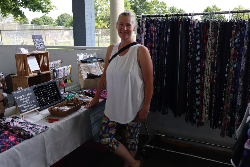 Woman posing with their colourful leggings - showcasing what is for sale at their booth