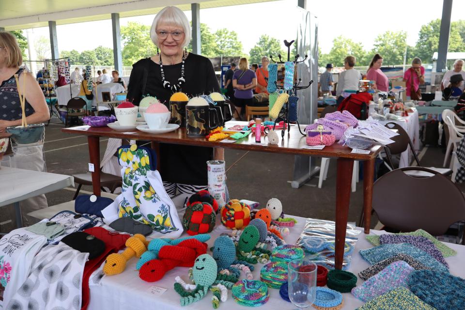 Woman standing behind their handmade knitted critters and clothing booth