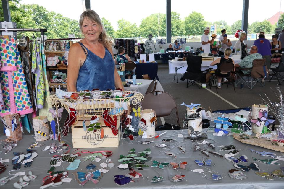 Woman standing behind their handmade stained glass table