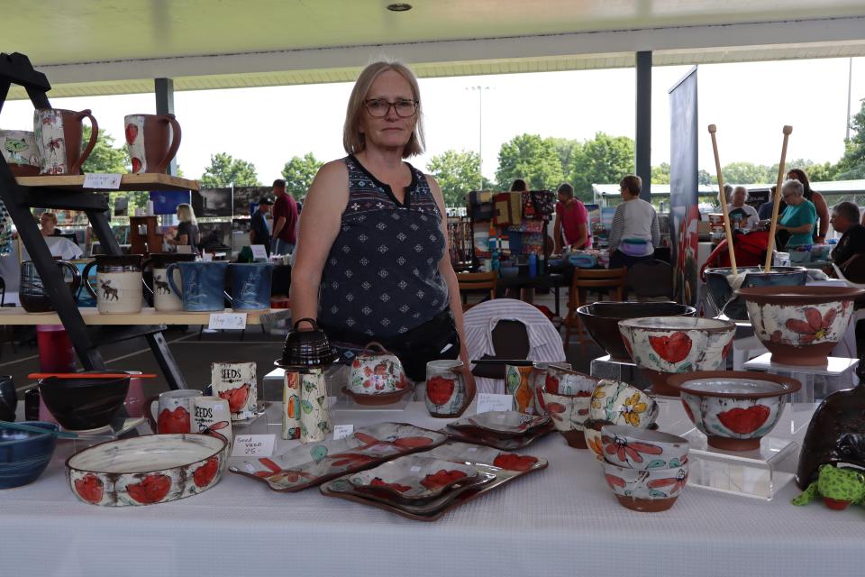 Woman standing behind their pottery booth