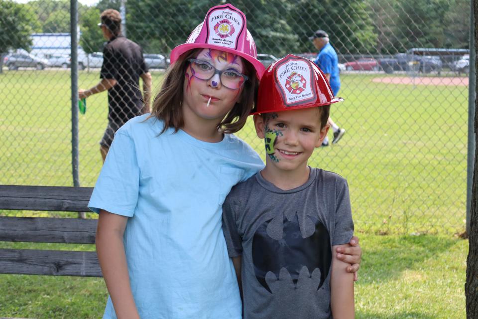 Young children posing together in their firefighter hats and facepaint