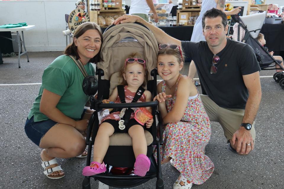 Young family with two girls all posing for a photo while exploring the vendor fair