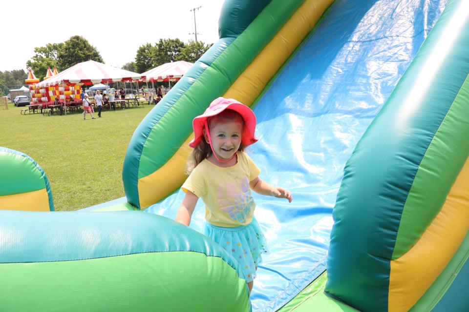 Young girl in a bright pink hat getting off of the inflatable