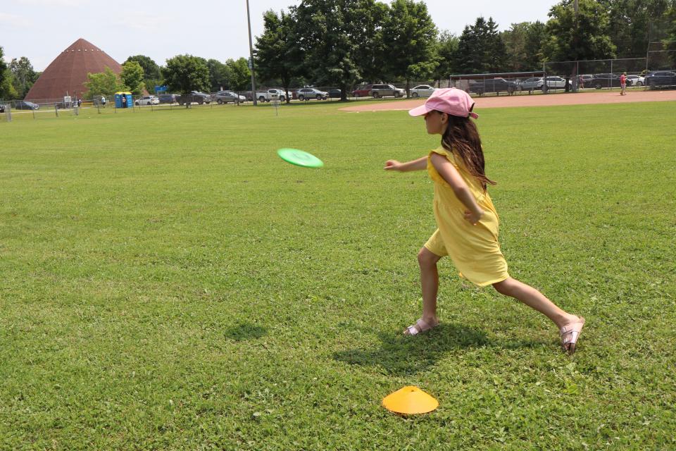 Young girl in a yellow dress throwing a frisbee