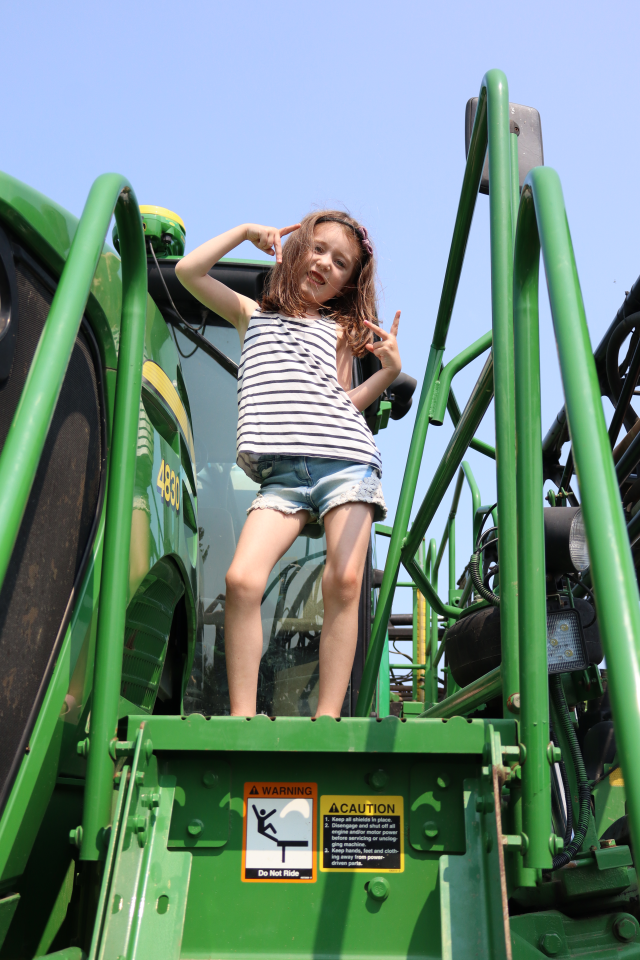 Young girl striking a pose on the large green tractor